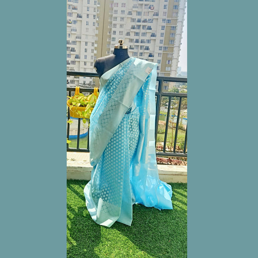 Benaras Soft Dhakai Saree in enchanting sky blue. Delicately adorned with intricate white boti detailing, this saree exudes timeless charm. Complete with a matching blouse piece, it's perfect for adding a touch of grace to any occasion - Fabcentra